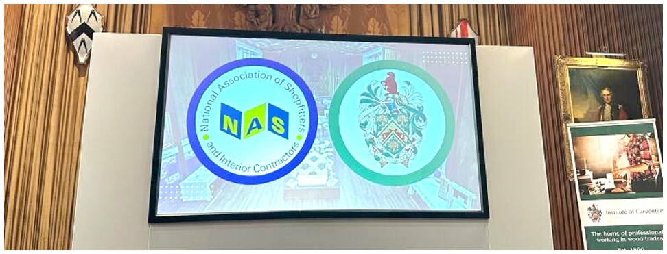 The NAS and IOC logos, shown on a presentation screen within the auditorium at Carpenters Hall.